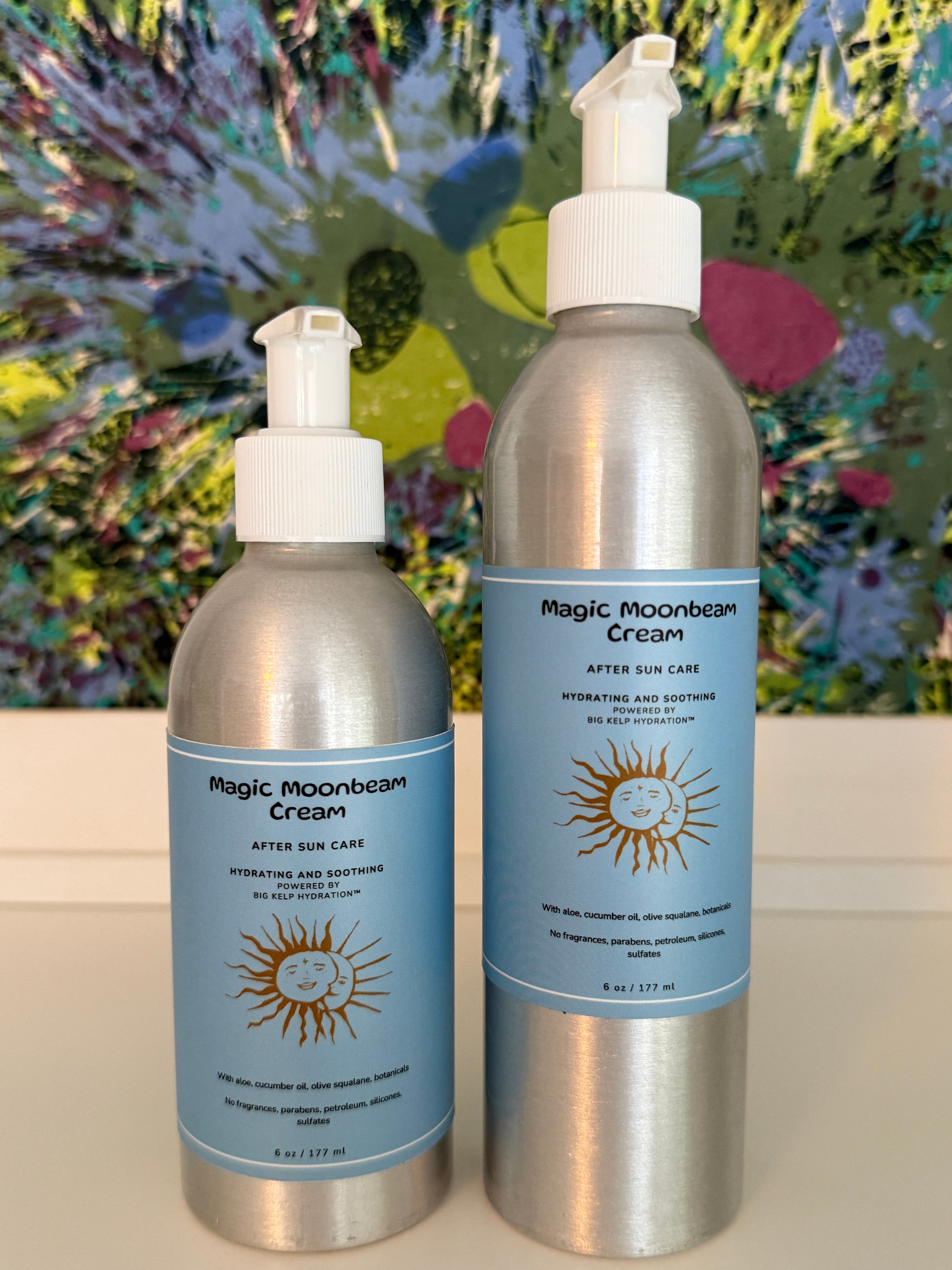Two bottles of Magic Moonbeam Cream on a white surface with a colorful abstract painting in the background.