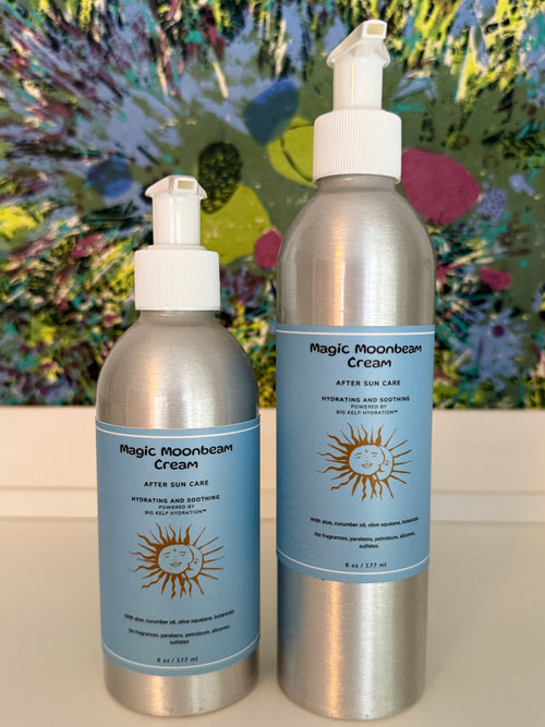 Two bottles of Magic Moonbeam Cream on a white surface with a colorful abstract painting in the background.